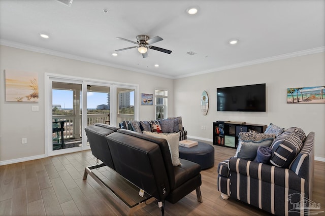 living room featuring wood finished floors, a ceiling fan, visible vents, baseboards, and crown molding