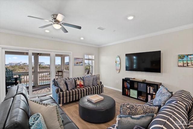 living area featuring visible vents, ornamental molding, and wood finished floors