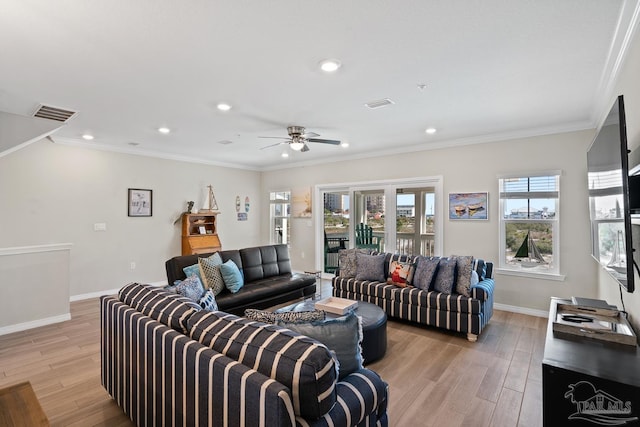 living room featuring light wood finished floors, visible vents, baseboards, ornamental molding, and a ceiling fan