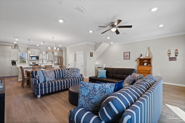 living room with light wood finished floors, visible vents, crown molding, baseboards, and ceiling fan with notable chandelier