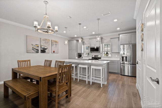 dining area with light wood-type flooring, visible vents, a notable chandelier, ornamental molding, and recessed lighting