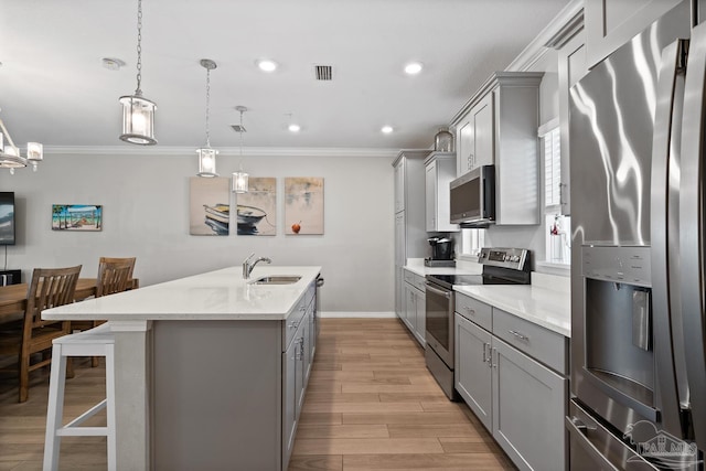 kitchen featuring light wood-style flooring, appliances with stainless steel finishes, gray cabinetry, and a sink