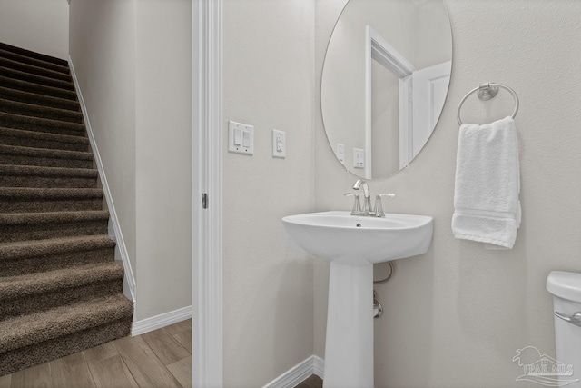 half bathroom featuring toilet, baseboards, and wood finished floors