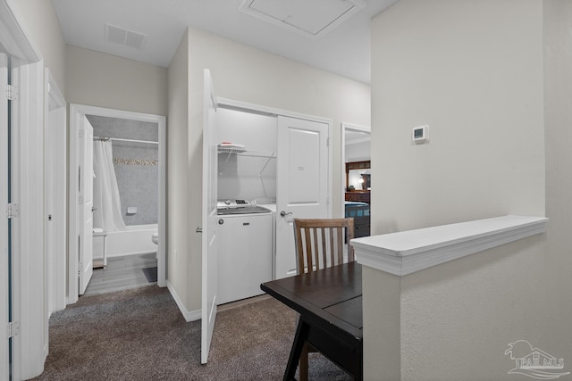 hallway with visible vents, baseboards, dark carpet, attic access, and washer and dryer