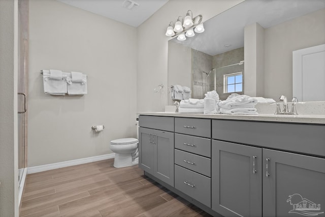 bathroom with toilet, a sink, wood finished floors, a shower stall, and baseboards