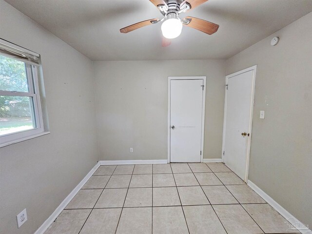 empty room with ceiling fan and light tile patterned floors