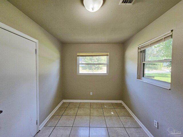 empty room featuring light tile patterned floors and a healthy amount of sunlight