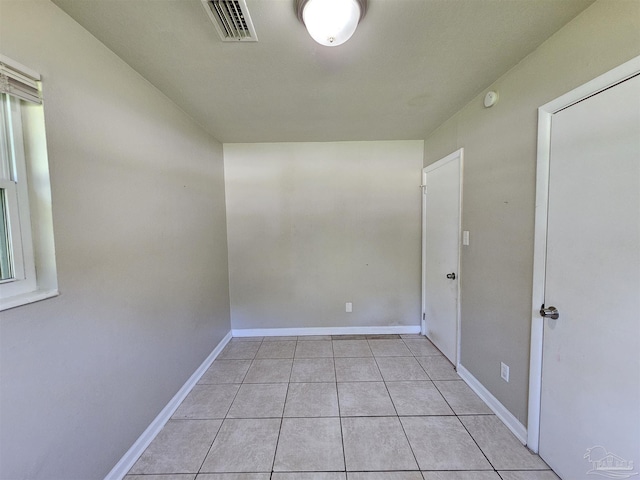 empty room with light tile patterned flooring, visible vents, and baseboards