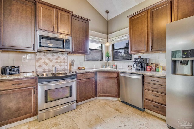 kitchen with tasteful backsplash, hanging light fixtures, sink, appliances with stainless steel finishes, and lofted ceiling