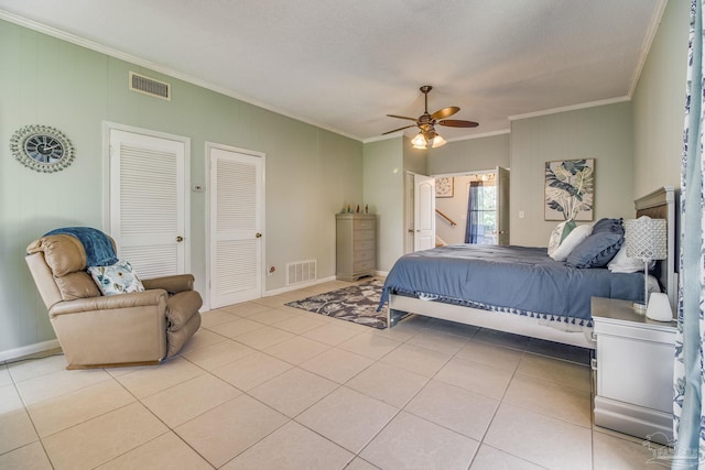 tiled bedroom featuring two closets, crown molding, and ceiling fan