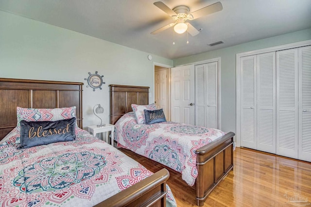 bedroom with ceiling fan, two closets, and light wood-type flooring