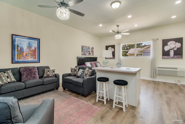 living room with ceiling fan, light hardwood / wood-style flooring, and a wall unit AC