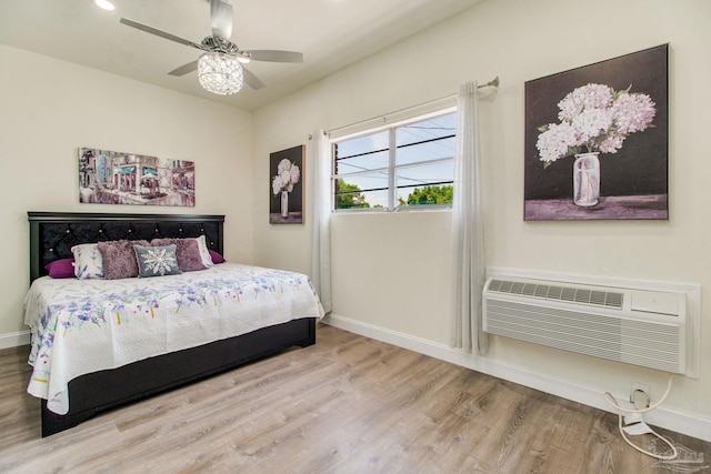 bedroom featuring a wall mounted AC, ceiling fan, and wood-type flooring