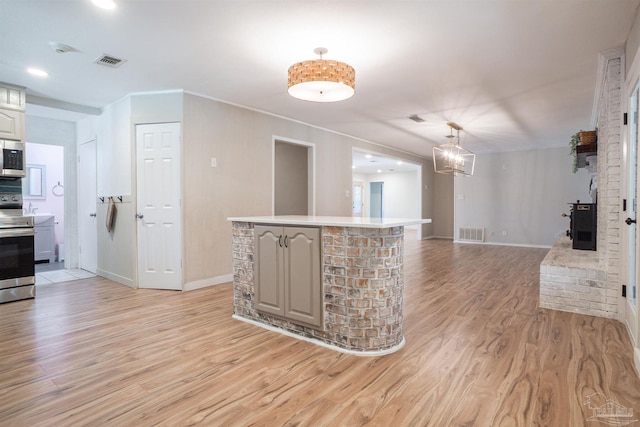 kitchen with decorative light fixtures, a chandelier, appliances with stainless steel finishes, a kitchen island, and light hardwood / wood-style floors