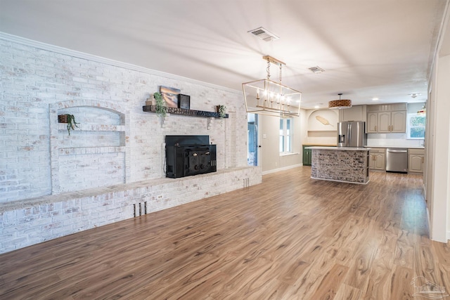 unfurnished living room featuring crown molding, brick wall, a wood stove, and hardwood / wood-style floors