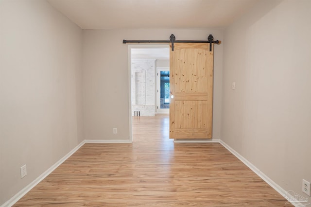 empty room with a barn door and light wood-type flooring