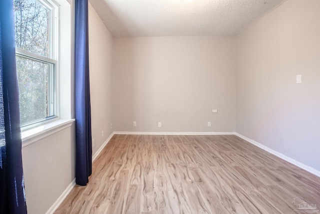 spare room with light hardwood / wood-style floors and a textured ceiling