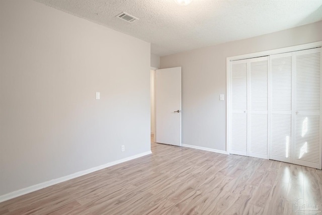 unfurnished bedroom with a closet, a textured ceiling, and light wood-type flooring