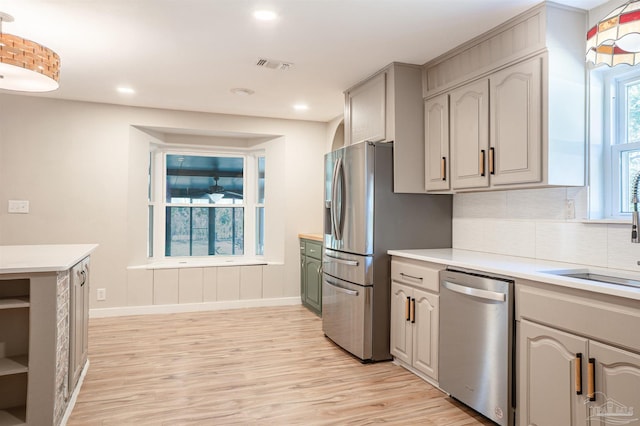 kitchen with sink, gray cabinets, stainless steel appliances, tasteful backsplash, and light hardwood / wood-style floors