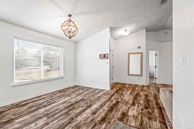 interior space with hardwood / wood-style floors, a textured ceiling, lofted ceiling, and a notable chandelier