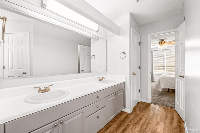 bathroom with ceiling fan, hardwood / wood-style floors, vanity, and a textured ceiling