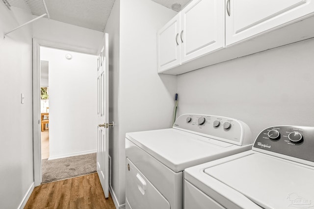 clothes washing area featuring washer and clothes dryer, dark hardwood / wood-style floors, cabinets, and a textured ceiling