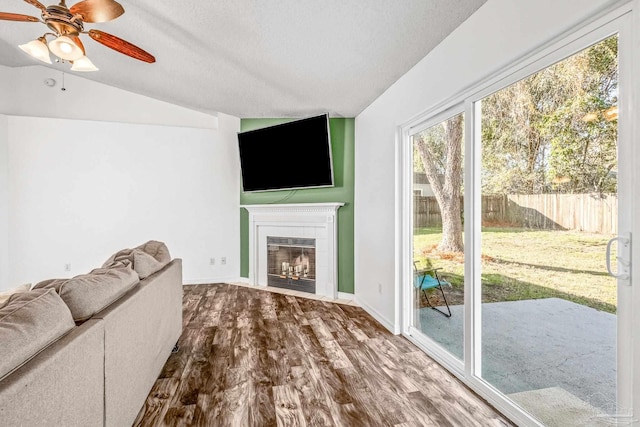 unfurnished living room featuring a textured ceiling, a tile fireplace, hardwood / wood-style floors, and lofted ceiling