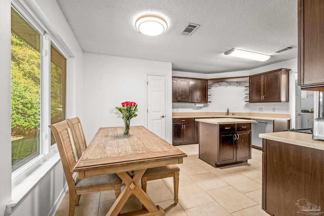 kitchen featuring dishwasher, a kitchen island, dark brown cabinetry, and a textured ceiling