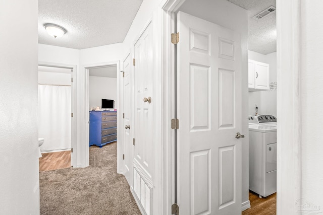 hall with washer and clothes dryer, carpet floors, and a textured ceiling