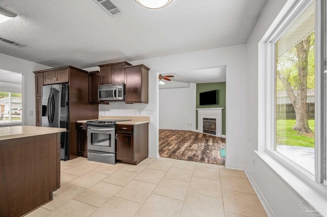 kitchen with dark brown cabinetry, visible vents, stainless steel appliances, and a ceiling fan
