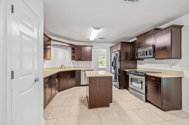 kitchen with light countertops, open shelves, a kitchen island, dark brown cabinets, and appliances with stainless steel finishes