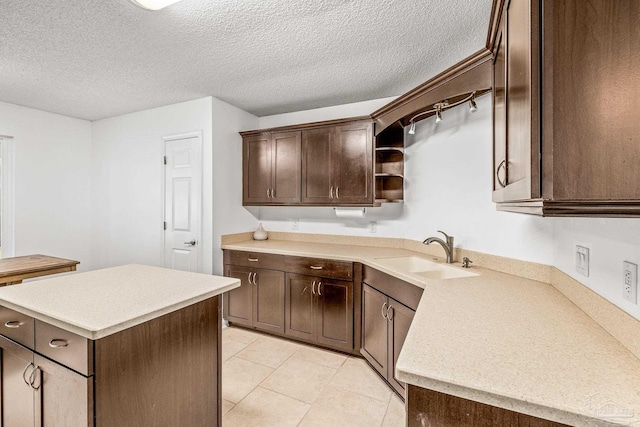 kitchen featuring dark brown cabinetry, sink, a center island, and a textured ceiling