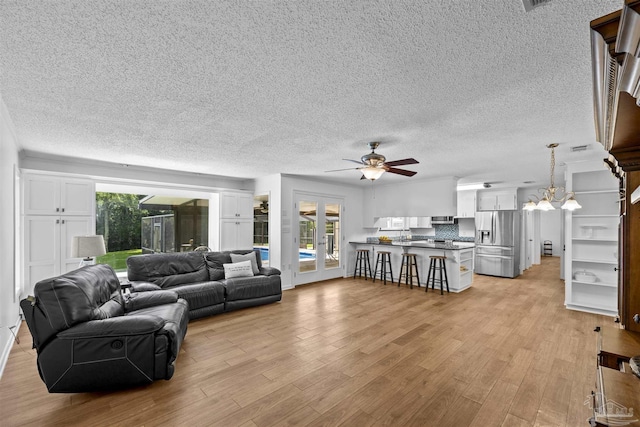1213 Tecumseh Pl, Pensacola, FL 32514 - living room featuring a textured ceiling, a ceiling fan, light wood finished floors, and a chandelier