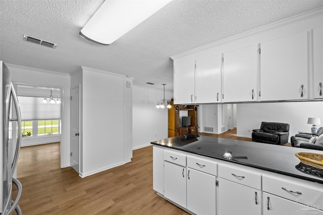 1213 Tecumseh Pl, Pensacola, FL 32514 - kitchen with a chandelier, a textured ceiling, freestanding refrigerator, light wood finished floors, and white cabinets