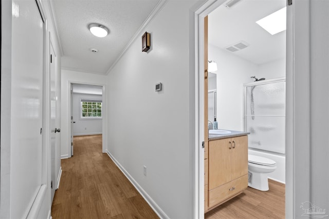1213 Tecumseh Pl, Pensacola, FL 32514 - hall featuring light wood-type flooring, ornamental molding, a textured ceiling, and a skylight
