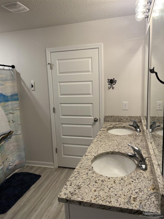 bathroom featuring double vanity, visible vents, wood finished floors, and a sink