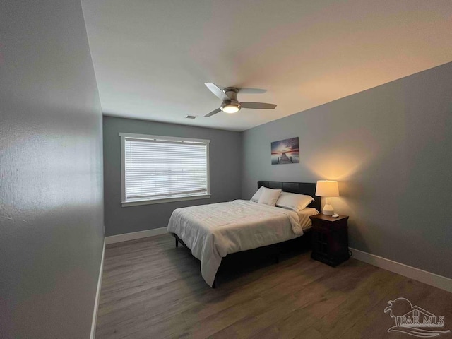 bedroom with dark hardwood / wood-style flooring and ceiling fan