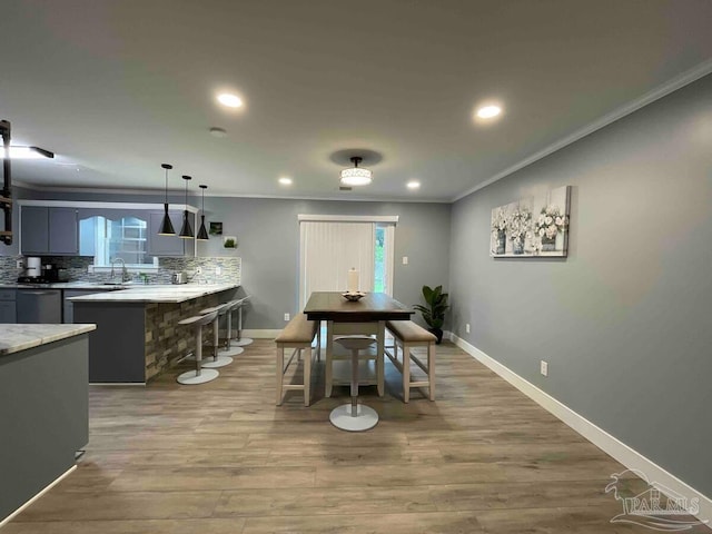 dining room featuring ornamental molding, sink, and light hardwood / wood-style flooring