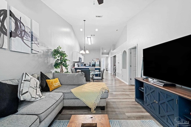 living area with light wood finished floors, a chandelier, ceiling fan, recessed lighting, and lofted ceiling