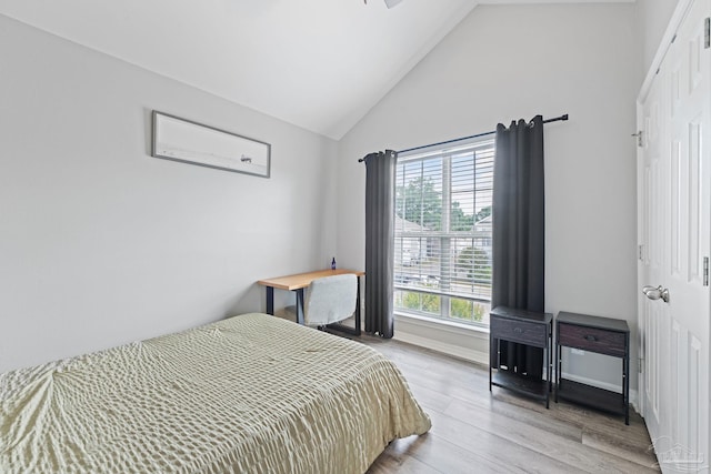 bedroom featuring light wood-style flooring, baseboards, and high vaulted ceiling