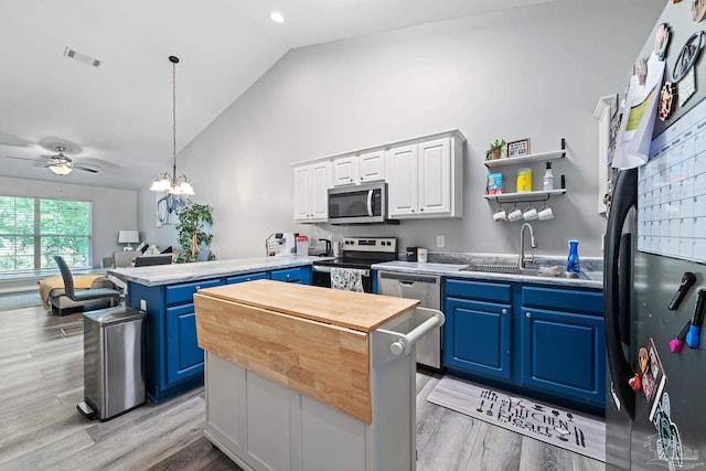 kitchen with appliances with stainless steel finishes, blue cabinets, a peninsula, vaulted ceiling, and a sink