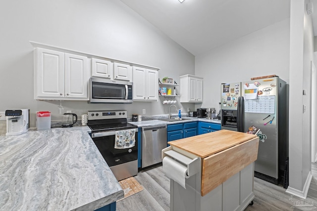 kitchen featuring appliances with stainless steel finishes, high vaulted ceiling, blue cabinets, a sink, and light wood-style floors