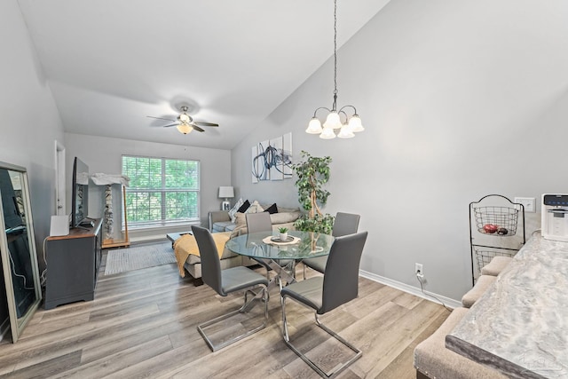 dining room with wood finished floors, a ceiling fan, a chandelier, baseboards, and high vaulted ceiling