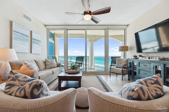 living area with expansive windows, ceiling fan, a textured ceiling, and visible vents