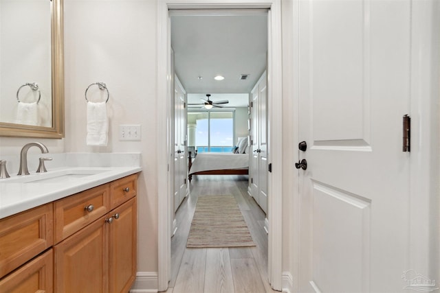 ensuite bathroom featuring a ceiling fan, wood finished floors, vanity, ensuite bath, and visible vents