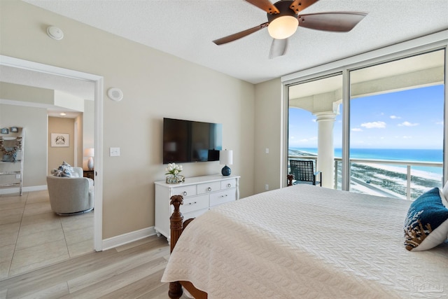 bedroom with a ceiling fan, a wall of windows, light wood-type flooring, baseboards, and access to outside
