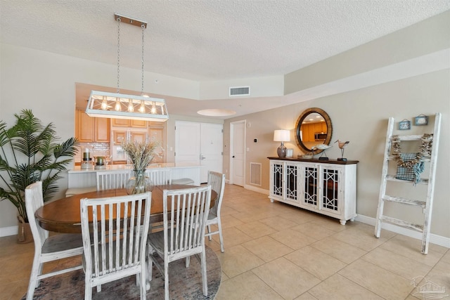 dining room with baseboards, a textured ceiling, visible vents, and light tile patterned floors