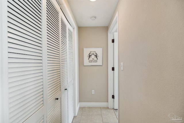 corridor featuring light tile patterned flooring and baseboards