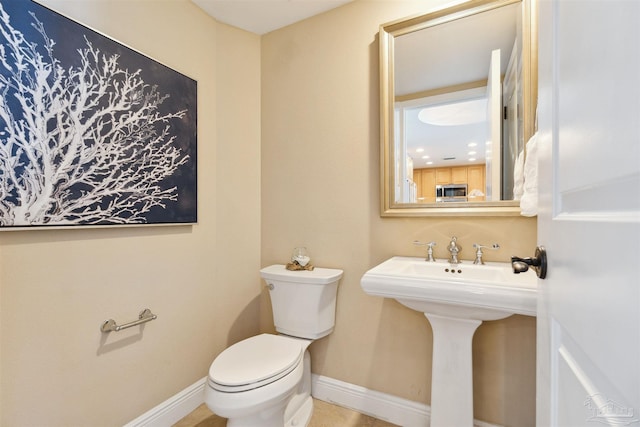 bathroom featuring toilet, a sink, and baseboards