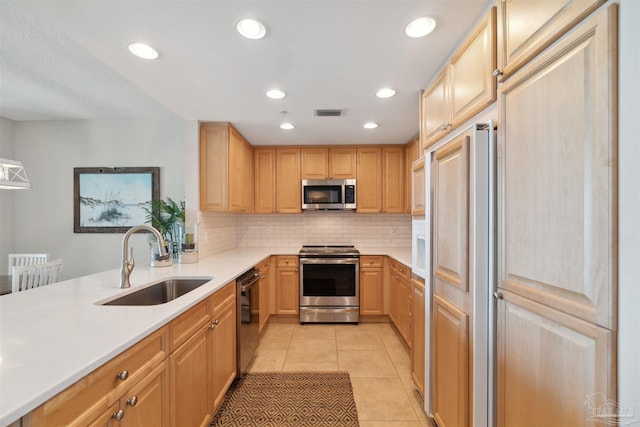 kitchen with a sink, light tile patterned flooring, stainless steel appliances, light countertops, and backsplash